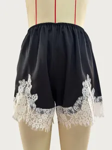 Close-up detail of the exquisite white eyelash lace trim on black satin wide leg shorts