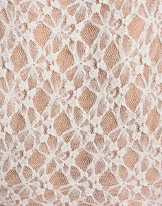 Macro view showing the intricate texture of white floral lace fabric with mesh details