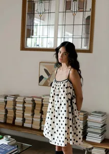 Detailed view of white polka dot summer dress with side ribbon tie in library setting