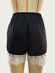 Detailed view of black satin shorts with exquisite white lace trim on the bottom hem