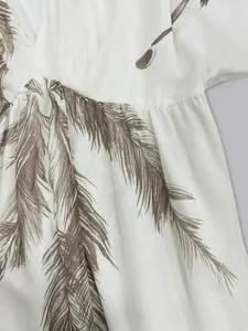 Close-up detail of bohemian white dress with brown feather print and waist gathering
