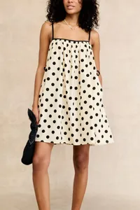 Elegant cream sleeveless mini dress featuring large black polka dots for casual summer wear