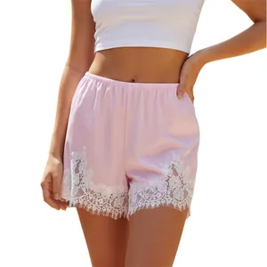 Detailed view of pink satin shorts with white lace trim and elastic waist