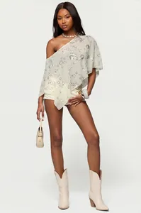 Détail d'un châle à paillettes à une épaule, porté avec des bottes pour un look d'été