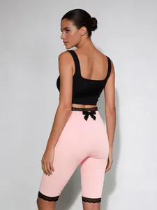 Detailansicht der eng anliegenden rosa Caprihose mit schwarzer Spitze und Schleife