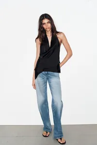 Dettaglio del top nero con scollo a V e design a pieghe incrociate per un look slim