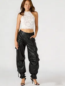 Dettaglio di un crop top bianco in pizzo con scollo all'americana e ricami eleganti.