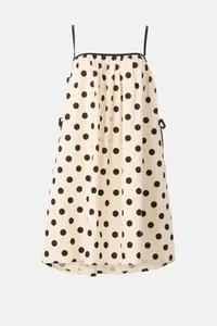 Detail view of summer cream polka dot dress with thin black spaghetti straps.