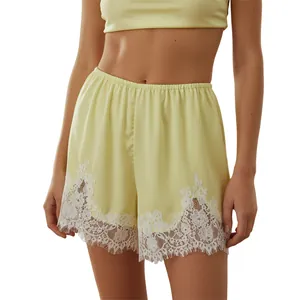 Detail of pale yellow loungewear shorts featuring elegant white lace trim and elastic waist.