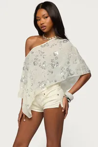 Vue détaillée d'un châle à paillettes blanc à une épaule avec des motifs floraux