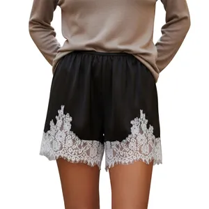 Elegant black satin shorts with white floral lace trim and wide-leg design