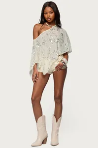 Modèle avec un poncho chic à paillettes à une épaule pour un look d'été bohème.