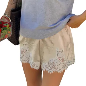 Close-up detail of champagne silk shorts featuring intricate white floral lace trim