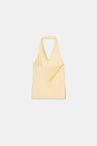 Dettaglio di un top giallo chiaro con scollo all'americana e pieghe incrociate