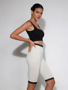 Details der schlanken Polka-Dot-Caprihose mit elegantem Spitzenbesatz und elastischem Bund