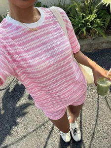 Scatto lifestyle all'aperto di un set in maglia a righe rosa e bianche con shorts