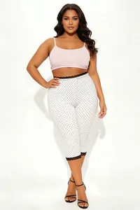 Detaillierte Ansicht der weißen Polka-Dot-Caprihose in Übergröße mit schwarzem Spitzenbesatz