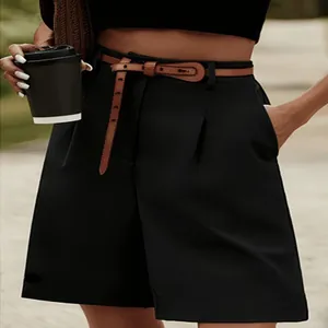 Detailopname van zwarte korte broek met hoge taille, plooien en een bruine riem.