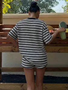 Vista posteriore di un set a due pezzi con t-shirt a righe bianche e nere e pantaloncini.