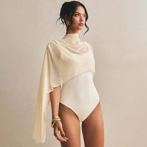 Close-up of elegant asymmetric mesh cape worn over a sleeveless white bodysuit.