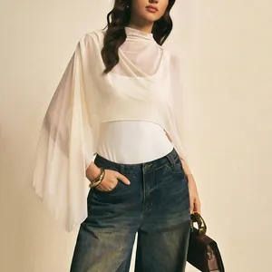 Close-up detail of a white sheer asymmetric mesh shawl layered over a sleek bodysuit