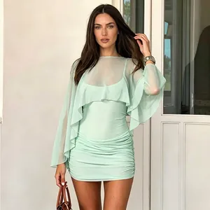 Detail view of mint green mesh mini dress featuring elegant ruching and sheer long sleeve shawl.