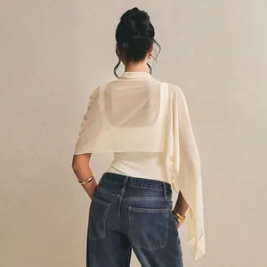 Detail view of asymmetric sheer mesh shawl paired with a slim-fit cream bodysuit