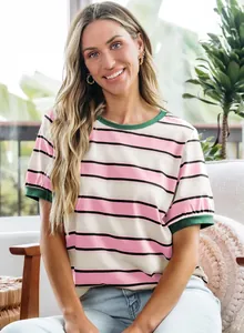 Detail of a striped pink and white T-shirt with green trim on a smiling model.