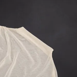 Close-up view of the breathable sheer cream mesh fabric on an asymmetric bodysuit.