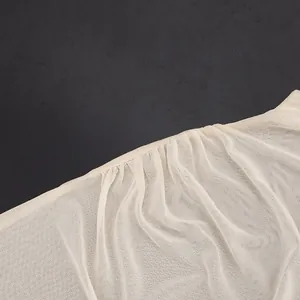 Close-up of lightweight beige mesh fabric with delicate pleated details on bodysuit