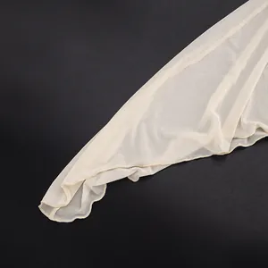 Detailed view showing the fine texture of sheer beige mesh fabric with lettuce edge.