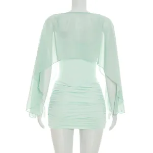 Detailed back view of a mint green ruched mini dress paired with a sheer mesh shawl