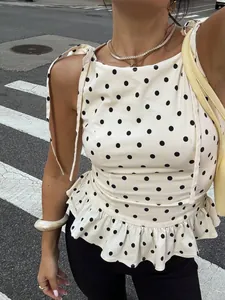 Detalle de blusa sin mangas con lunares blancos, dobladillo con volantes y lazos