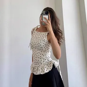 Elegante blusa sin mangas de lunares con cuello redondo y dobladillo con volantes