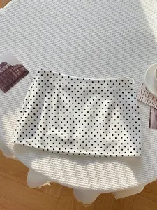 Detailansicht eines sexy schwarz-weißen Minirocks mit Polka Dots auf einem strukturierten Tisch