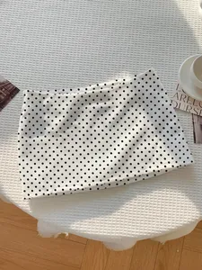 Nahaufnahme eines weißen Minirocks mit schwarzem Punktmuster auf weißem Hintergrund
