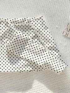 Detailaufnahme des modischen weißen Minirocks mit schwarzen Punkten und Stoffstruktur