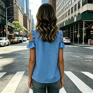 Back view detail of a light blue cold-shoulder blouse with ruffled sleeves on a city crosswalk