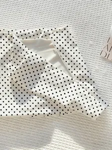 Detailansicht eines weiß-schwarz gepunkteten Bodycon-Minirocks mit feiner Stoffstruktur.