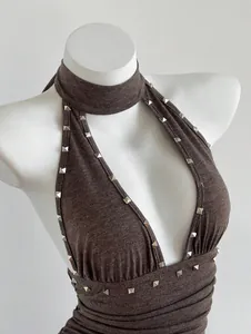 Detalle de un vestido marrón halter sin mangas con tachuelas metálicas cuadradas