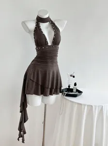 Detalle del vestido marrón con cuello halter, tachuelas y falda fruncida.