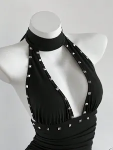 Detalle de vestido negro tipo halter con adornos de tachuelas metálicas cuadradas plateadas