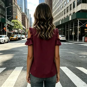 Detailed back view of a burgundy cold-shoulder top featuring ruffle sleeves in an urban setting
