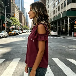 Side view of a burgundy cold-shoulder top with ruffle sleeve detail in a city setting