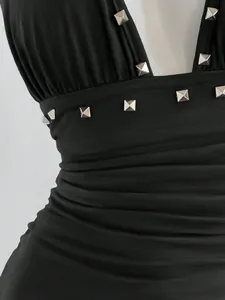 Primer plano de un vestido halter negro con tachuelas plateadas y un diseño fruncido