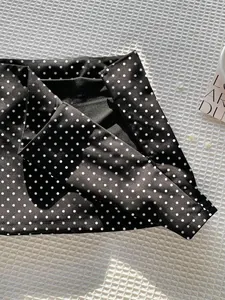 Detailansicht eines schwarzen Minirocks mit Polka-Dot-Muster und doppellagigem Design.