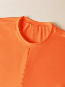 Primer plano detallado del cuello redondo y la tela suave de este top corto naranja