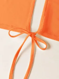 Detalle de top corto naranja vibrante con nudo central y cierre de lazo frontal.