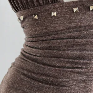 Primer plano de vestido halter fruncido marrón con tachuelas cuadradas plateadas y tela jaspeada