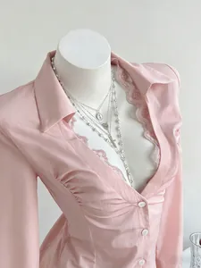 Elegant pink V-neck long sleeve shirt with delicate lace trim details on a mannequin